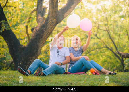 Vieux couple reading newspaper in jardin au coucher du soleil. Couple amour aîné Concept. Banque D'Images