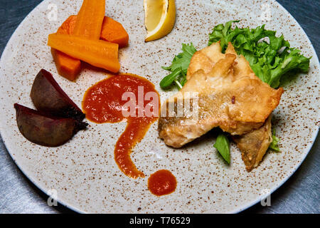 Du poisson cuit au four avec des légumes, de la salade et du citron. Banque D'Images