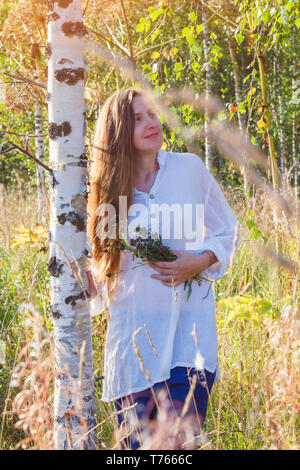 Jeune fille en vêtements traditionnels recherche près de Birch dans la forêt d'automne. Scène d'automne Banque D'Images