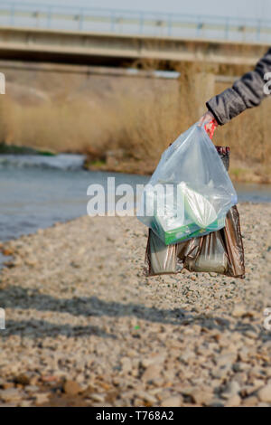 Les déchets dans la nature, le nettoyage de l'environnement au printemps sur la rivière à partir de la poubelle une femme en bleu à usage unique en latex à grand bleu en mitaines Banque D'Images