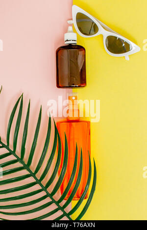 Sunblock sur bouteille carrée jaune lumineux et fond rose. Le concept de la station en mer, l'heure d'été. Haut de la vue, télévision lay, minimalisme, copy space Banque D'Images