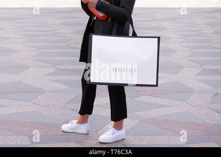 Fille avec sneakers blanc debout tenant un sac Gucci dans une rue. Copenhague, Danemark - 4 mai 2019 Banque D'Images