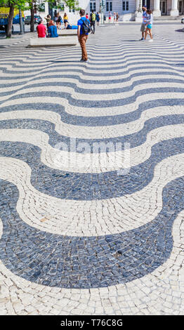 Les touristes marche sur pavés avec motif vagues, Lisbonne, Portugal Banque D'Images