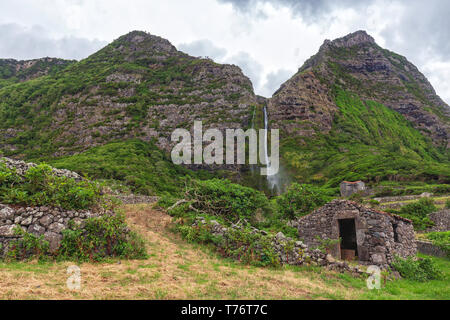 Un vieux bâtiment rock et la Cascata do Poco Bacalhau près de Faja grande dans les Açores. Banque D'Images