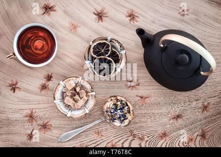 Thé Floral mise à plat. Théière, tasse, les tranches de citron et de fleurs sur fond de bois. Banque D'Images