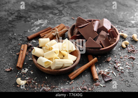Bols avec morceaux de chocolat et des bâtons de cannelle sur fond sombre Banque D'Images