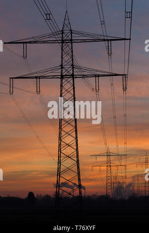 Silhouette de lignes à haute tension et les pylônes menant à une centrale électrique à vapeur devant un ciel coloré après le coucher du soleil. Karlsruhe, Allemagne Banque D'Images