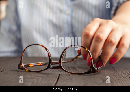 Main tenant une femelle brown lunettes encadrées Banque D'Images