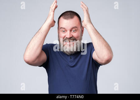 Homme mûr en bleu t-shirt expressif gesticulant avec mains, essayant de prouver son opinion. Banque D'Images