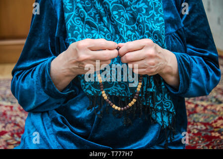 Chapelet musulman dans les mains d'une vieille femme en prière dans une robe et foulard, Ramadan Banque D'Images