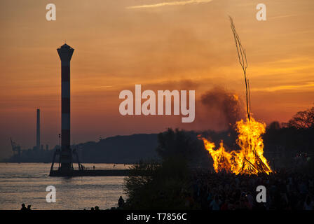 Feu de Pâques dans le coucher du soleil, dans l'arrière-plan le phare de Blankenese (Hambourg, Allemagne). Les feux de Pâques ont été une tradition en Blankenese au cen Banque D'Images