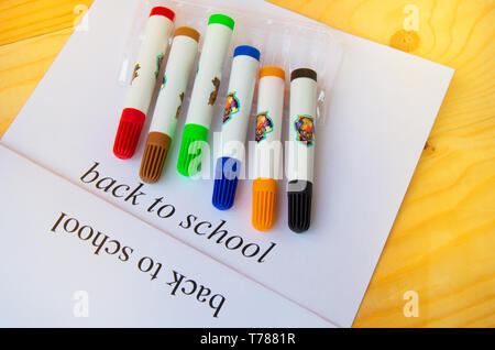 Retour à l'école. Feuille de papier avec texte et marqueurs de couleur sur un fond de bois, vue du dessus. Banque D'Images