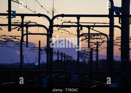 Le Mont Fuji s'élève au-dessus de nuages à coucher du soleil, avec les chemins de fer et de mâts pour la Tsukuba Express Line à Moriya Gare au premier plan. Banque D'Images