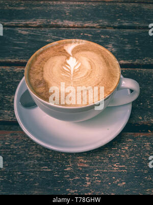 Image de tasse de lait avec du café latte art sur fond de bois. Belle tasse en céramique, mousse, de haut en bas vue, tonification, élégante place pour le texte Banque D'Images