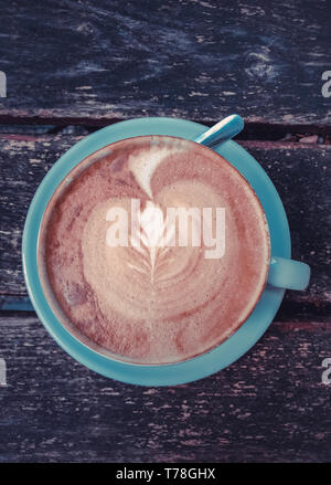 Image de tasse de lait avec du café latte art sur fond de bois. Belle tasse en céramique, mousse, de haut en bas vue, tonification, élégante place pour le texte Banque D'Images