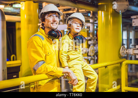 Jeune homme et un petit garçon sont tous deux dans un uniforme de travail jaune, verres, et le casque dans un environnement industriel, plate-forme d'huile ou de gaz liquéfié plant Banque D'Images