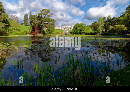 À la recherche sur le lac et les jardins de Powerscourt House a sunlit, l'Irlande, avec un reflet dans l'eau entre l'eau de nénuphar Banque D'Images