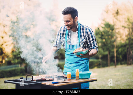 Heureux homme préparer la viande barbecue dans la nature Banque D'Images