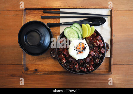 Steak de thon sur le riz avec des oeufs sur table en bois de style japonais Banque D'Images