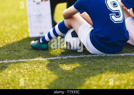 Jeune joueur de football au cours de session de formation. Enfants Sittion sur vert Football. Arrière-plan de coaching de soccer. Sports Education Banque D'Images