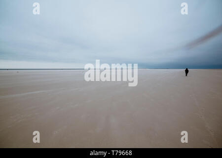 Personne au milieu d'une large plage de sable contre paysage ciel couvert sur moody journée à la mer du Nord, Amrum, Nebel, Allemagne, Schleswig-Holstein Banque D'Images