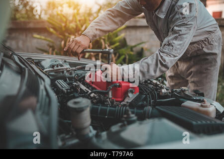 Le jeune mécanicien auto contrôle moteur et réparer Banque D'Images