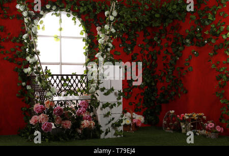 Zone de photo, l'emplacement des balançoires de jardin, décorées de fleurs pour le mariage. Contre un mur rouge vif de fleurs de verdure. Banque D'Images