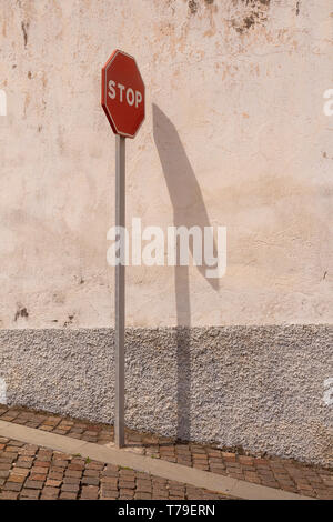 Vue latérale sur le panneau d'arrêt de la circulation avec son ombre sur un mur. Arico Nuevo, Tenerife, Canaries, Espagne. Banque D'Images