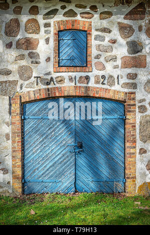 De portes en bois d'une ancienne grange en pierre avec toiture en bois situé dans la campagne de Le Skane région. Banque D'Images