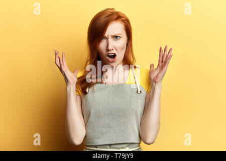 Frustrés girl in apron exprime ses émotions négatives. la photo en gros. sensation, frutration, serveuse de réprimandes, les clients de jeunes femelles garderner shout Banque D'Images