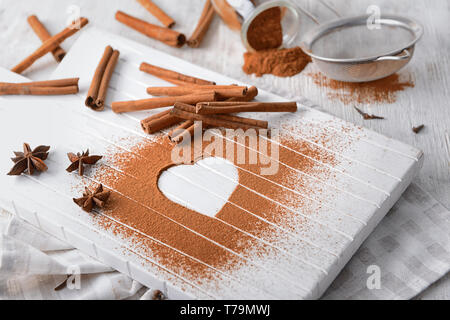 La composition avec des bâtons de cannelle, d'anis étoile et coeur en poudre sur planche de bois Banque D'Images