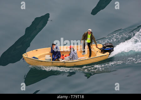 Trois sections locales de règlement dans le sud du Groenland Aappilattoq croisière salue les passagers de leur bateau à moteur. Banque D'Images