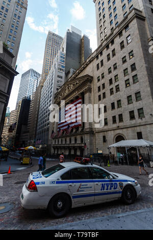 Une voiture de police du NYPD est garée dans la rue devant la Bourse de New York, qui est décorée de drapeaux américains. Banque D'Images