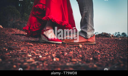 Couple d'âge moyen avec des pieds en gros plan des chaussures en cuir rouge et rouge robe volants en atteignant pour kiss Banque D'Images