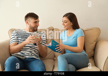 Jeune couple d'argent comptant à l'intérieur. Concept d'épargne de l'argent Banque D'Images