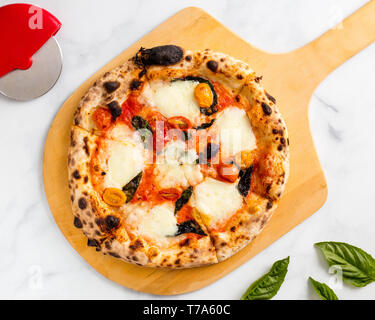 Four bois Pizza Mozzarella frais sur une pizza peler avec un arrière-plan en marbre blanc Banque D'Images