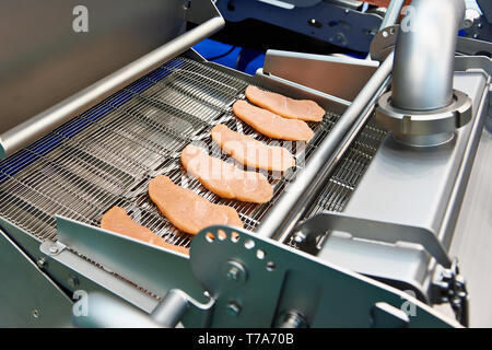 Des morceaux de viande sur une courroie de convoyeur sec machine Panure Banque D'Images