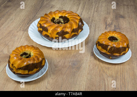 Sweet golden cuit en gâteaux. Dessert au Chocolat en tranches sur la table. Délicieux petit déjeuner sur assiettes en porcelaine blanche. Coco cacao frais pasty portions. Banque D'Images