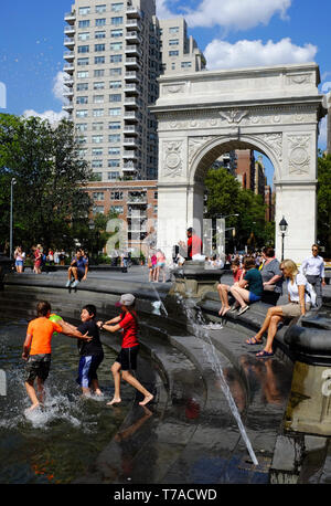 Les gens en phase de refroidissement dans et par la fontaine à Washington Square Park avec Washington Square Arch dans l'arrière-plan.New York City.USA Banque D'Images