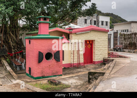 Hong Kong, Chine - 7 mars, 2019 : Tai O village de pêcheurs. Lieu de culte taoïste jaune et rose avec en face l'offre four à entrée est de la vill Banque D'Images