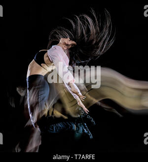 Une jeune femme de race blanche danseur moderne isolé sur fond noir avec le light painting flou de l'effet de vitesse Banque D'Images