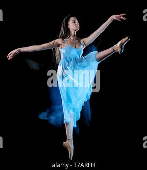 Une jeune femme de race blanche ballerine danse isolé sur fond noir avec le light painting flou de l'effet de vitesse Banque D'Images