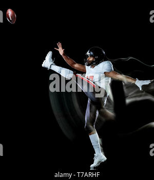 Un african american football player man studio shot isolé sur fond noir avec la lumière la peinture avec l'effet de vitesse de mouvement floue Banque D'Images