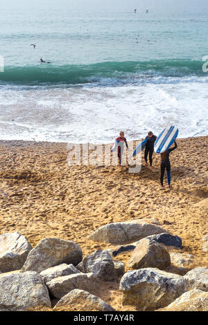 Jeunes surfeurs avec leurs planches de surf et de marcher à l'extérieur de la mer sur la plage de Fistral à Newquay en Cornouailles. Banque D'Images