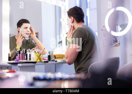 Curieux mec tatoué à l'essai de nouveaux masque de visage alors qu'il était assis dans le studio Banque D'Images