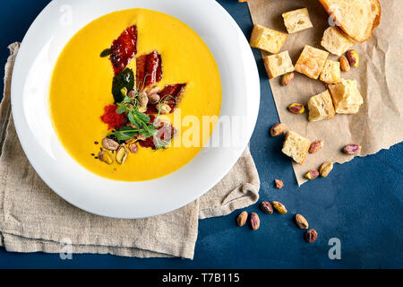 Soupe au potiron avec du poulet et de pistaches. Fond bleu, close-up Banque D'Images