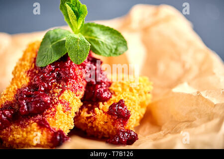 Le fromage, cuit dans la pâte, couverte de confiture de framboises. Se trouve sur parchemin, close-up. Belle lumière arrière. Banque D'Images