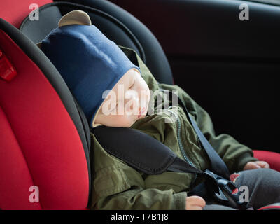 Close Up portrait of cute baby garçon endormi dans un siège de voiture. Sécurité enfant voyageant sur la route. Moyen sûr de voyager attaché leur ceinture de sécurité dans un véhicule Banque D'Images