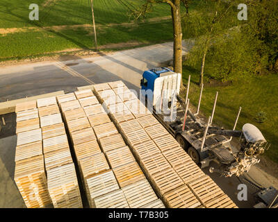 Vue aérienne du site scierie avec palettes en bois empilés et camion garé à côté de lui Banque D'Images