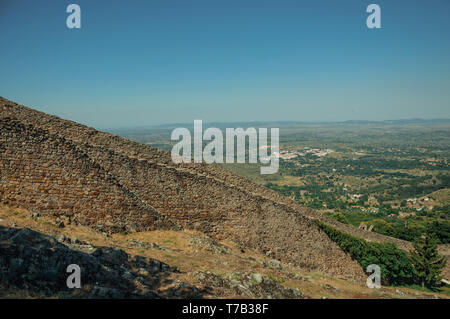 Mur de pierre extérieur solide long passant le long de la colline, avec en arrière-plan du paysage de campagne à Marvao. Un hameau médiéval perché sur un rocher au Portugal. Banque D'Images